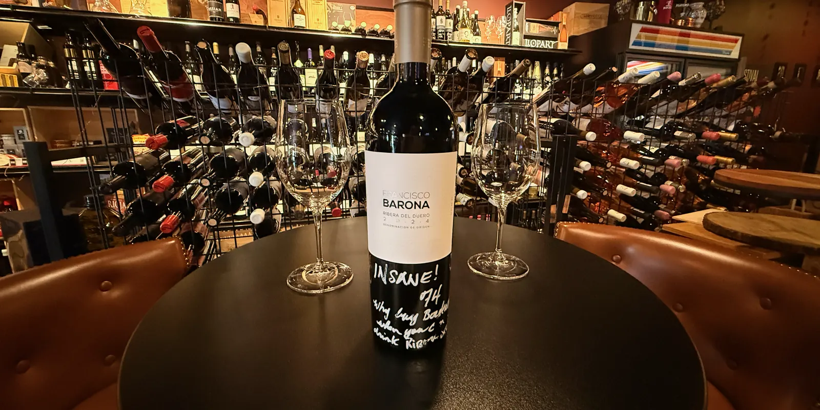 A bottle of Francisco Barona, Ribera del Duero, on a round table between two glasses, with Victor’s handwritten note on it: “Insane! 74”