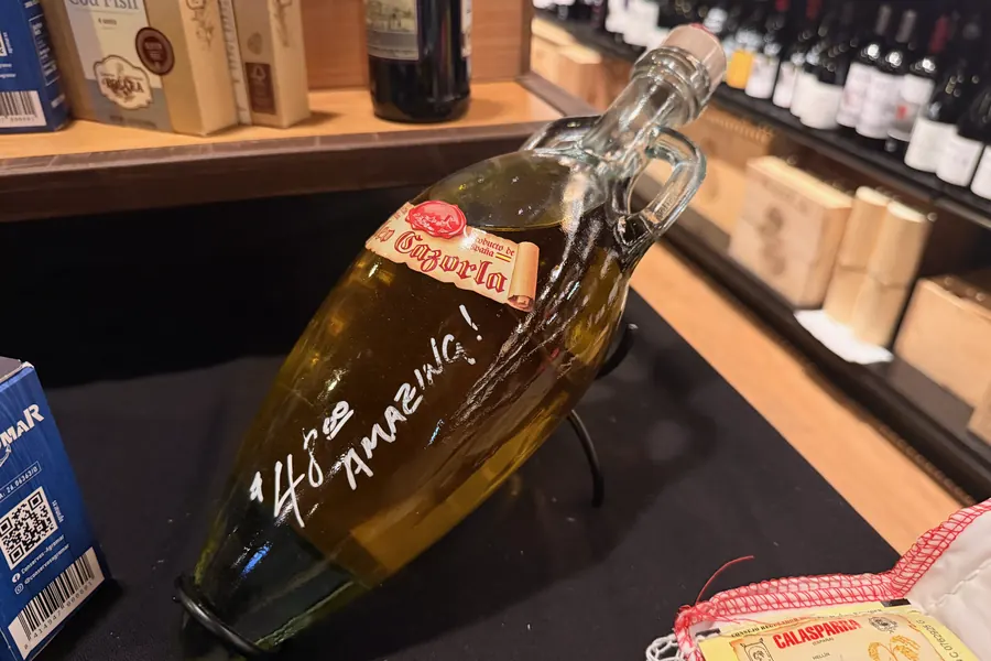 A swing-top bottle of Spanish olive oil at La Vid marked “$14.99, Amazing!” in white marker