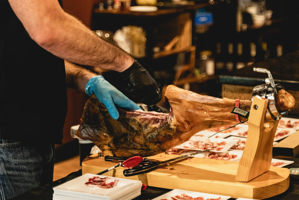 Jamón ibérico being carved by hand on a stand at La Vid