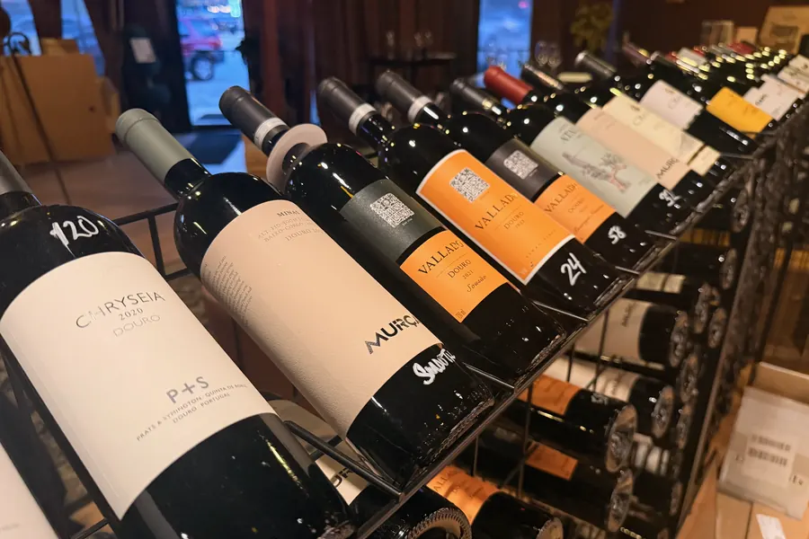 Douro reds racked at an angle at La Vid: Chryseia P+S and other bottles with handwritten prices
