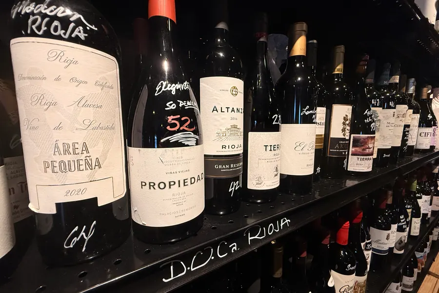 La Vid’s Rioja shelf: Área Pequeña, Propiedad, Altanza, and Tierra bottles above a row marked D.O.Ca. Rioja, with Victor’s handwritten prices