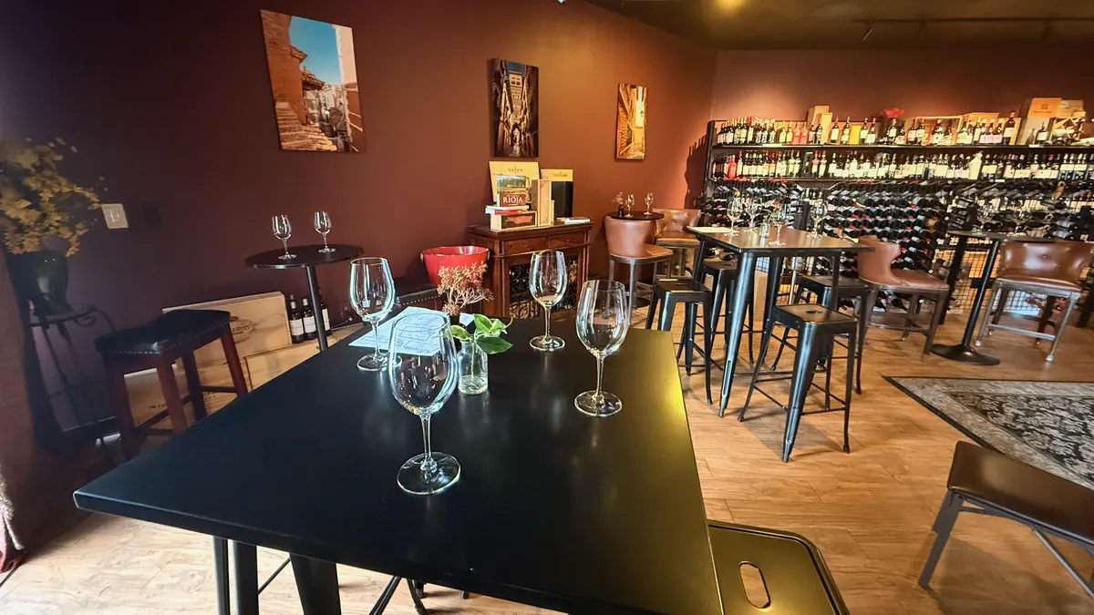 Tables set with wine glasses under paintings of Spain, the wine wall along the back of the room