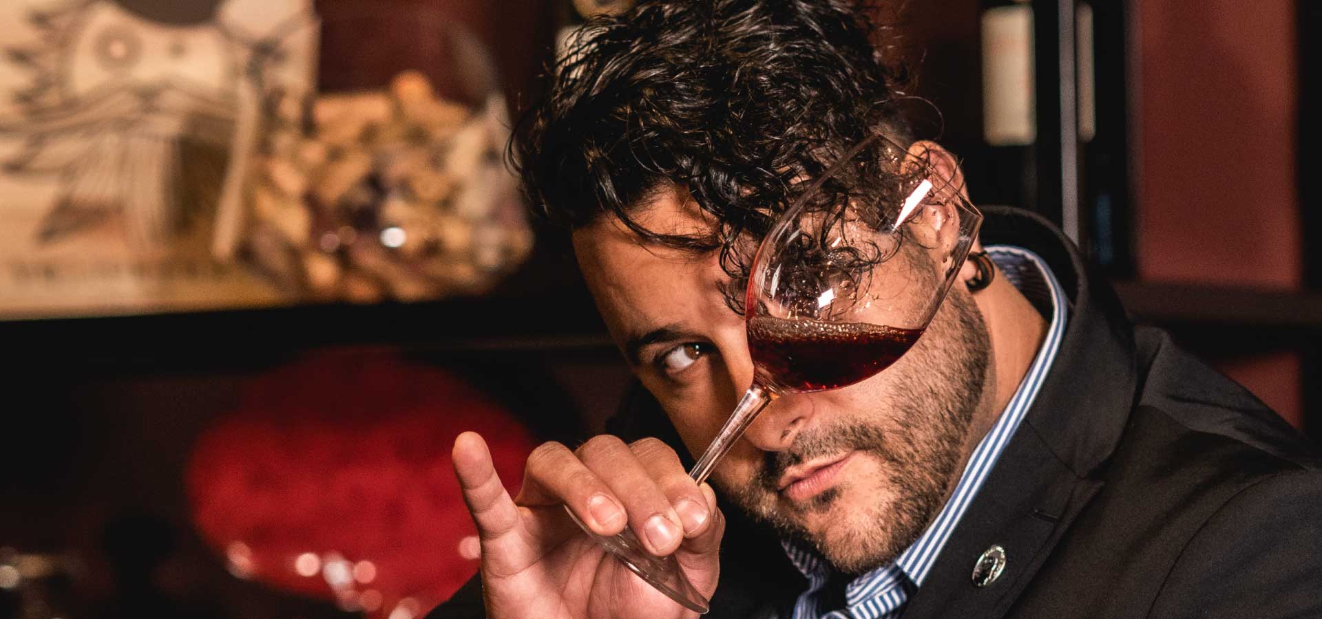 Victor examining the color of a red wine by tilting the glass at eye level