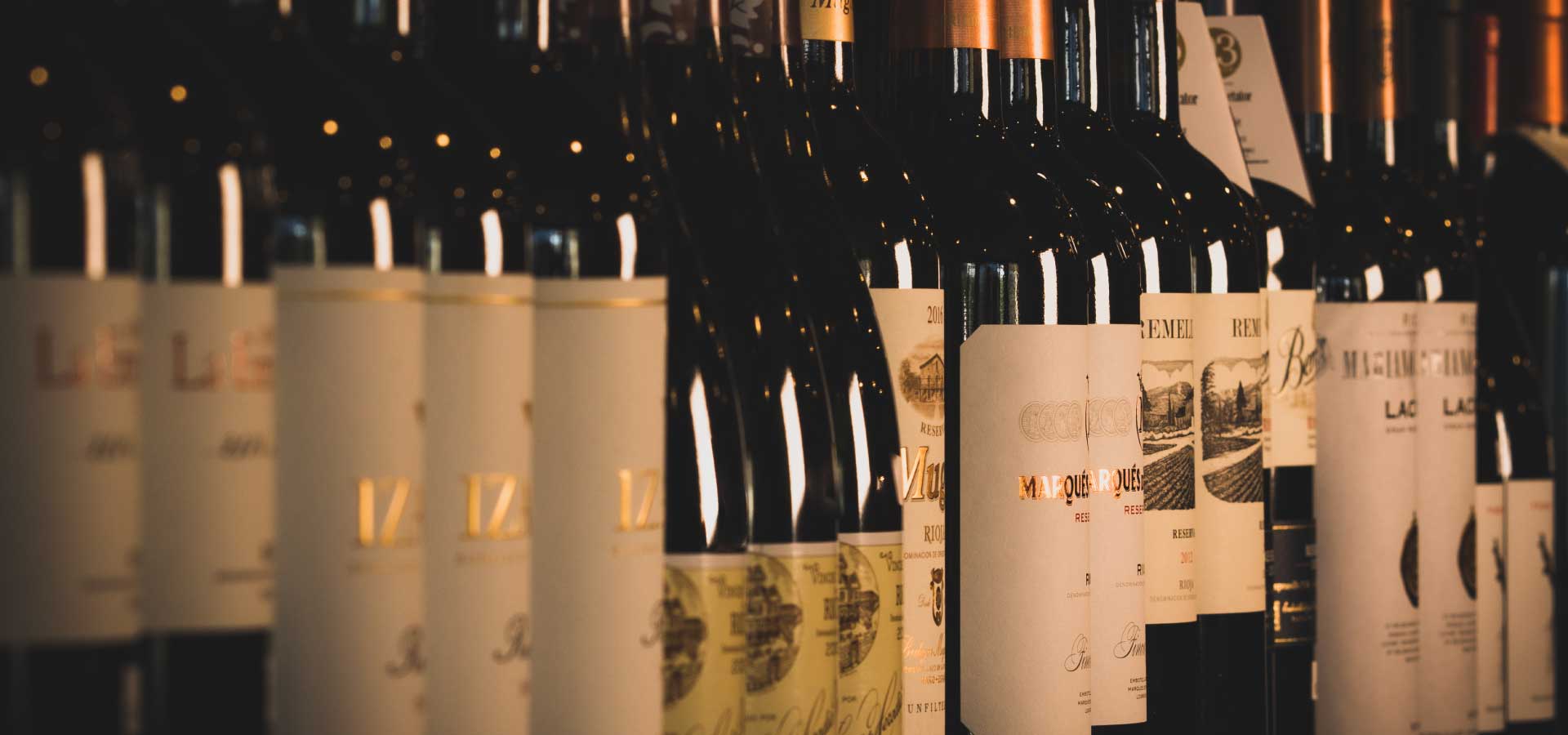A row of Rioja bottles from producers like Muga and Marqués de Riscal on the shelf at La Vid